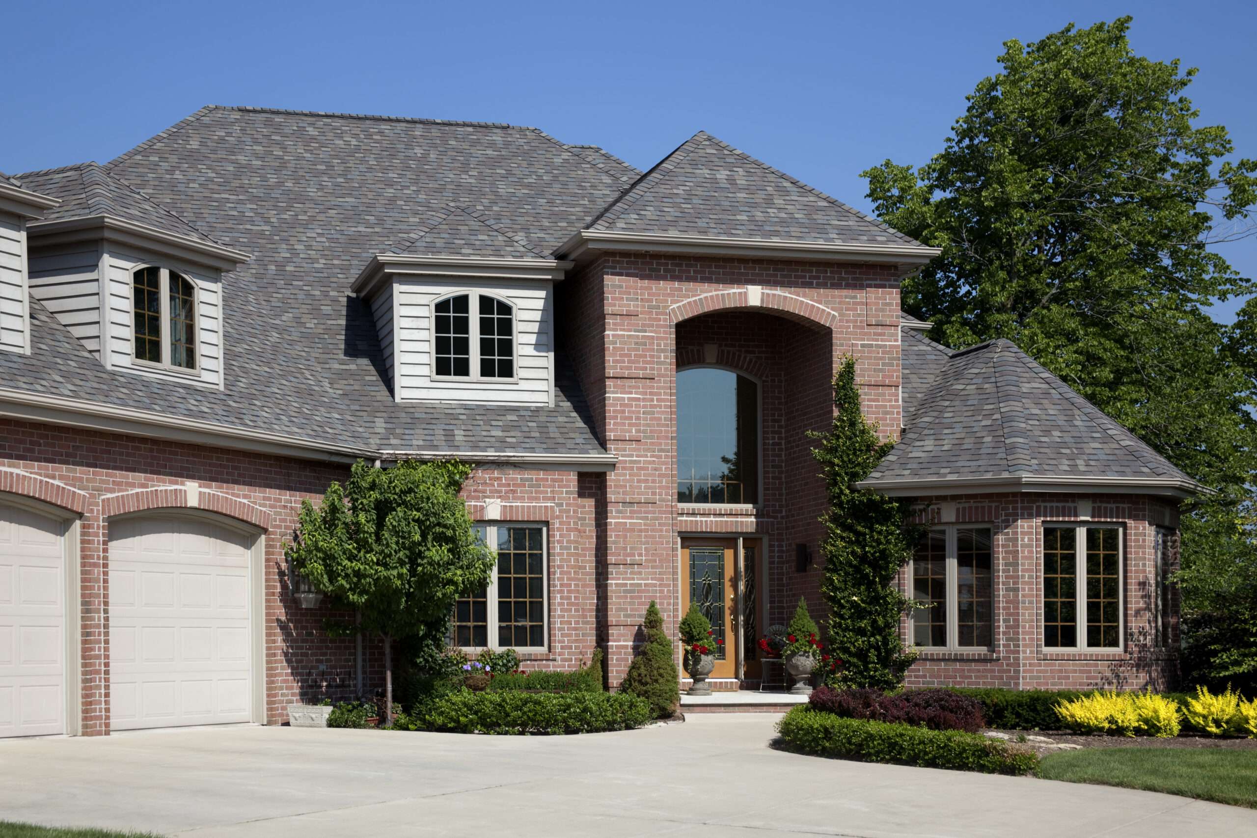 Elegant brick house with lush landscaping and garage
