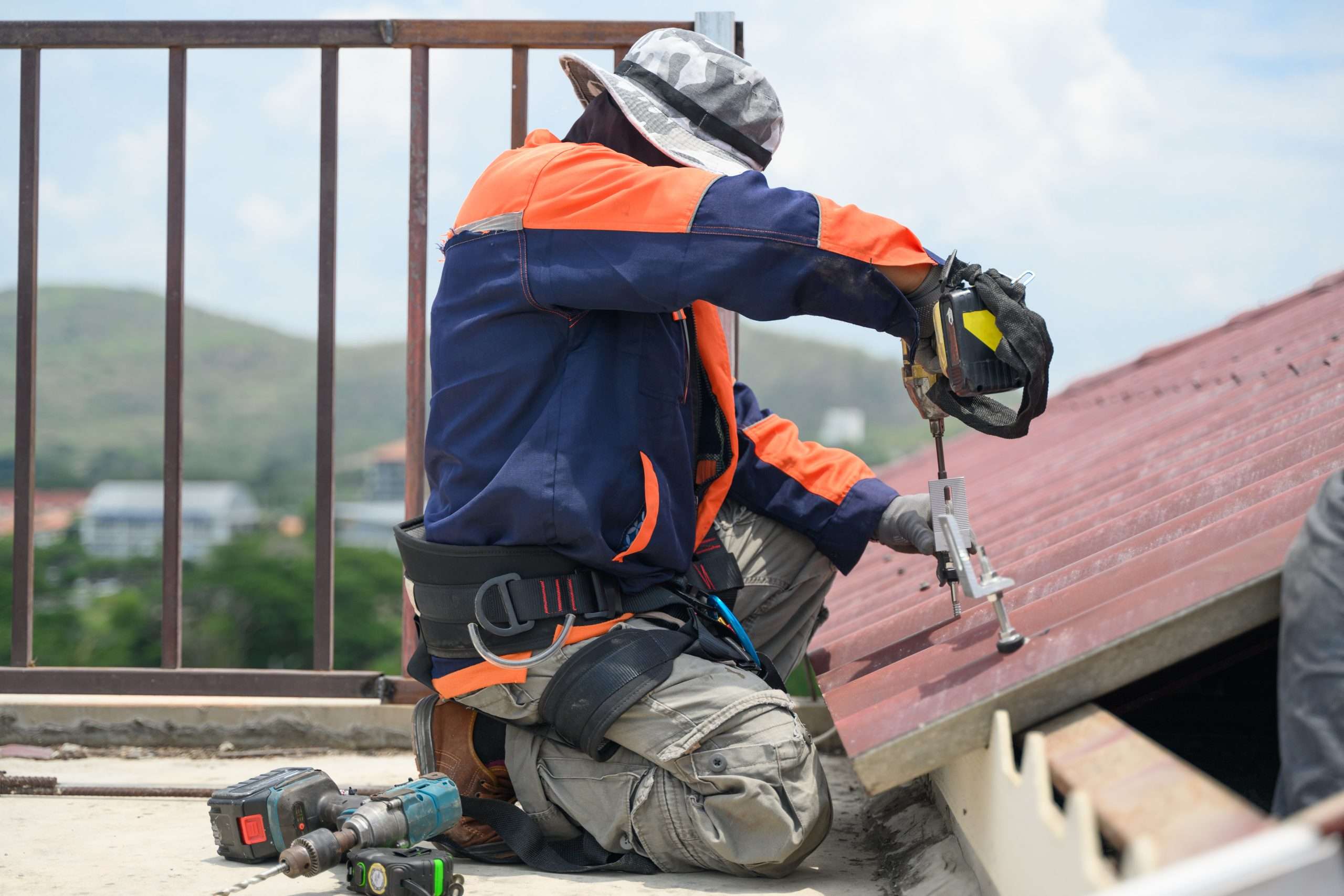 Worker drilling on a rooftop with safety gear